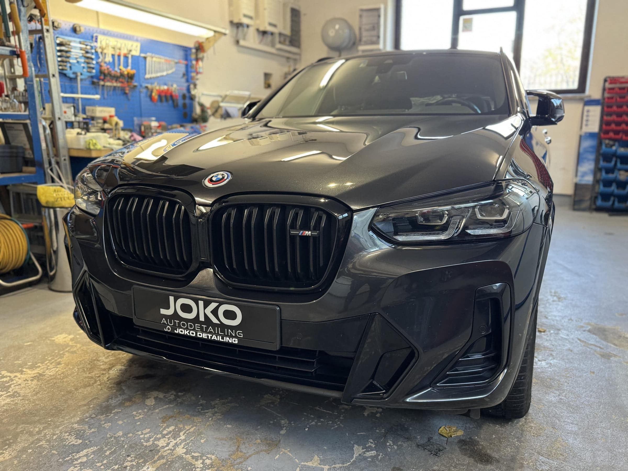 Przód BMW X4 M z tablicą JOKO Autodetailing w studiu